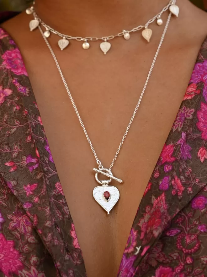 Silver heart toggle necklace with red stone layered with mini leaf choker by Loft & Daughter