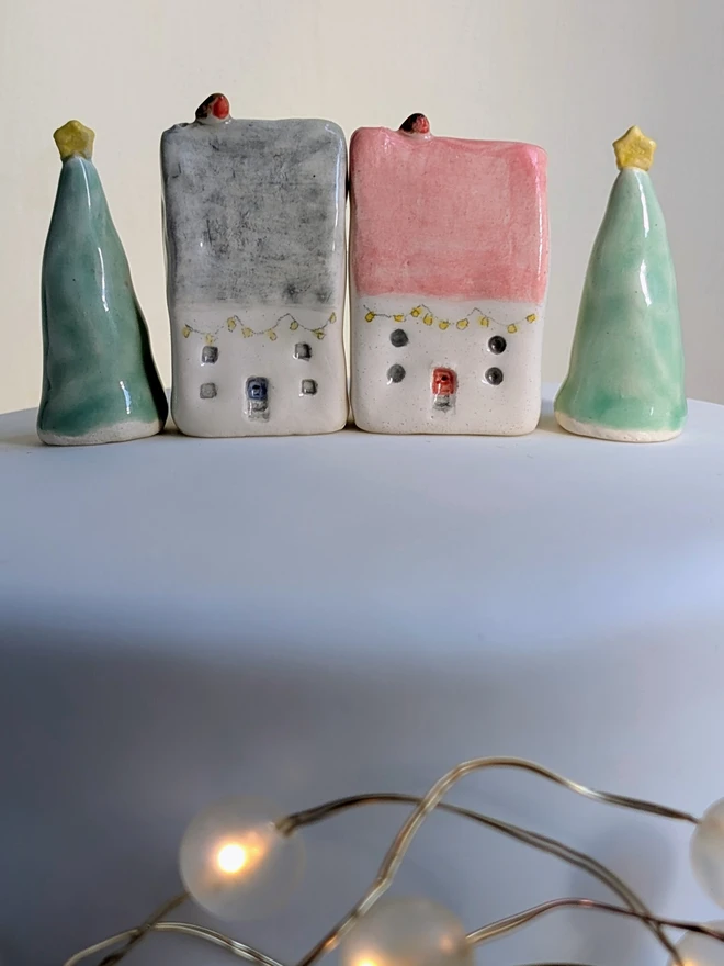 miniature ceramic house with robin and tree cake topper ornament on a white Christmas cake