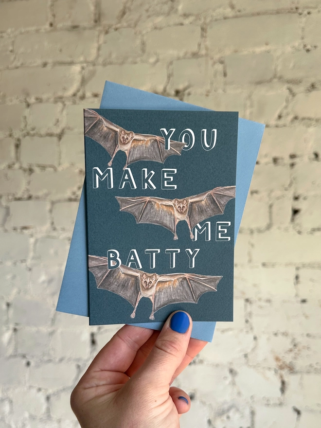 deep blue card featuring a realistic illustration of three bats and the text "You Make Me Batty" with a blue envelope