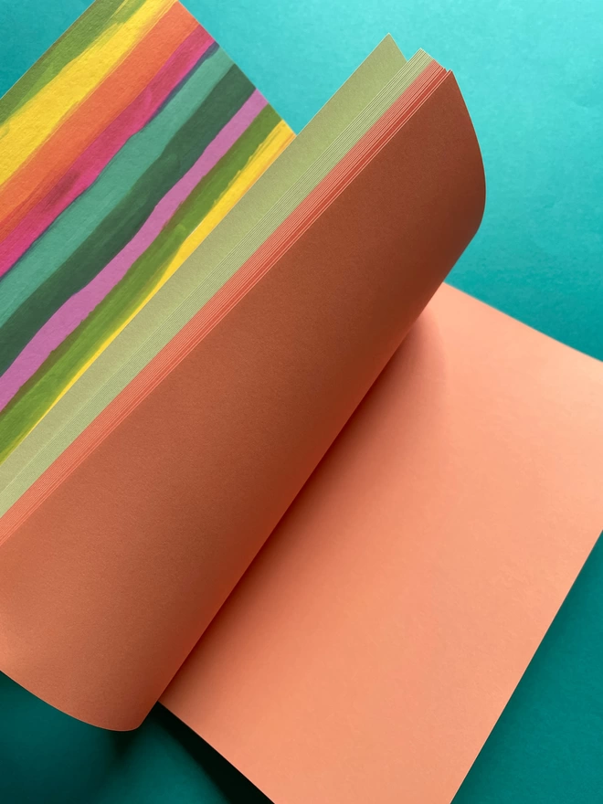 Inside view of the A5 notebook. Showing the rainbow paper sections of the notebook, including a minty green, and coral