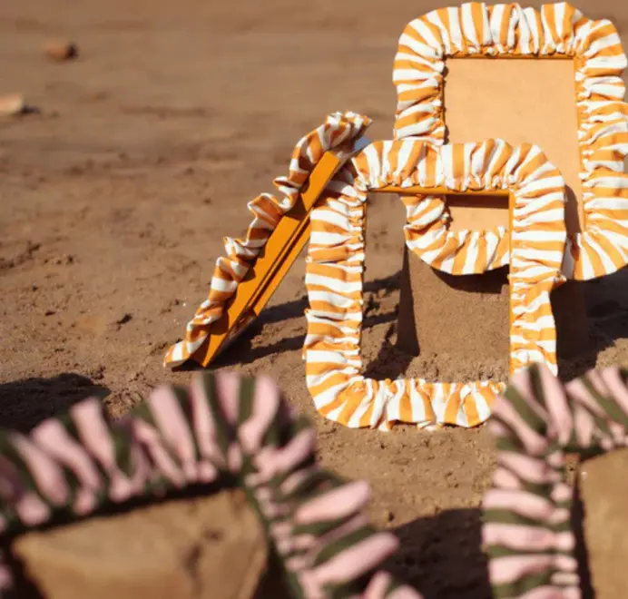 Soft ruffled frames with mustard-and-white striped fabric trim on the beach. 