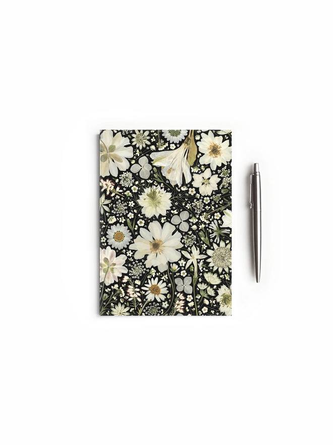 Floral Notebook with cover design created from pressed white flowers on a black background.