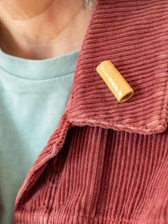 ceramic pasta pin badges. a ceramic rigatoni badge photographed on a jacket.
