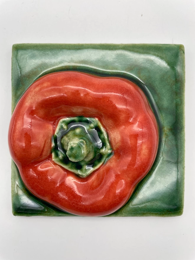Handmade ceramic tile taken from a plaster cast of a real pepper, top view with stalk. Very realistic, three-dimensional, with lush coloured glazes.