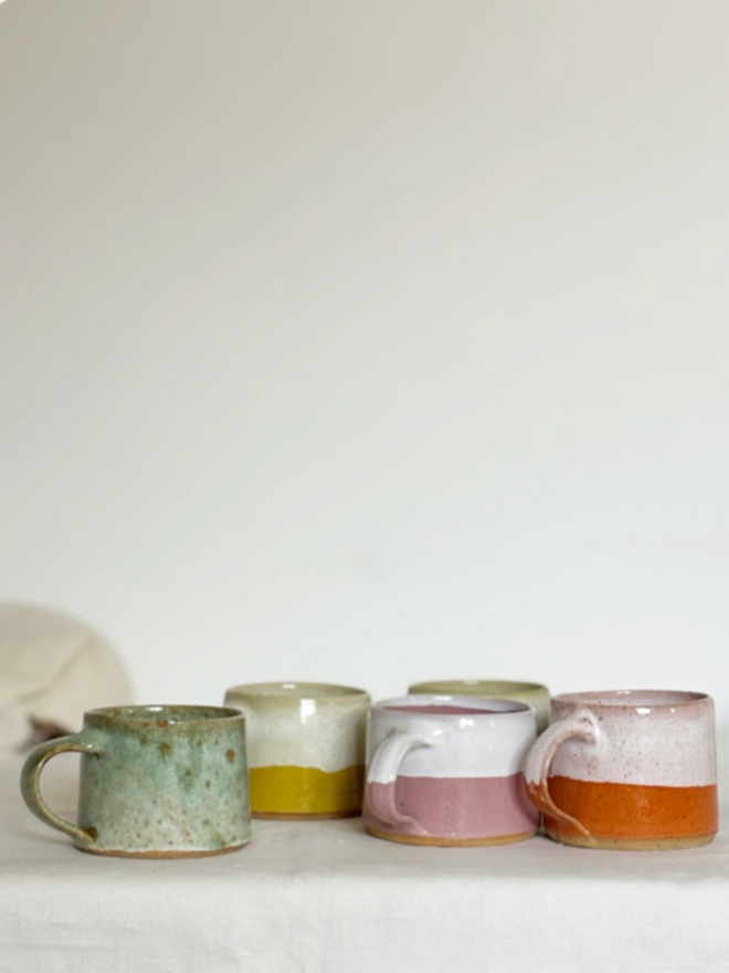 Espresso Mug. A selection of five Espresso Mugs in, from left to right, Green, Yellow, Pink, Blue (behind), and Orange.