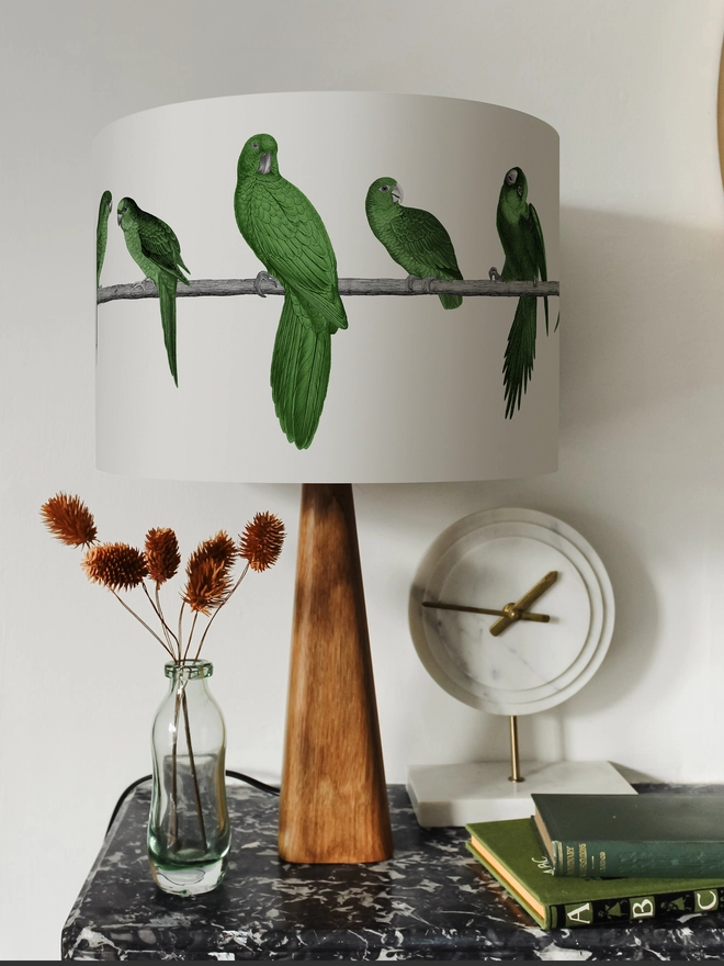 A colourful lampshade featuring a lively group of green parrots in a tropical jungle-inspired design, bringing a playful touch to home interiors.