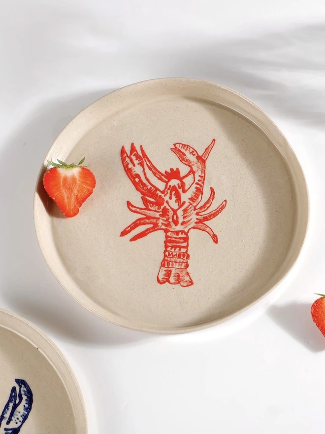 Handmade Ceramic Side Plate With Red Lobster Design, a side plate with a red lobster design on a white table. 