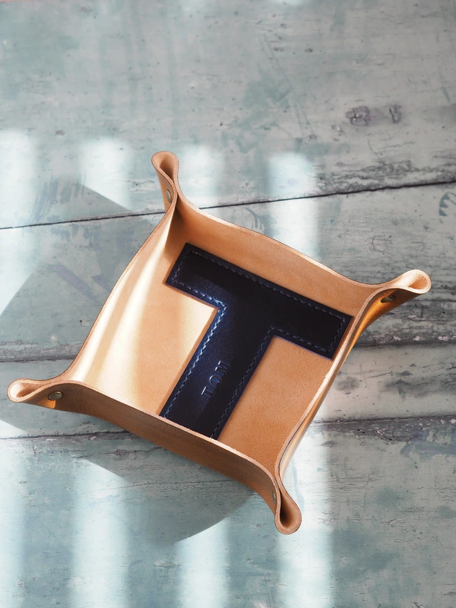 Personalised Letter Coin Tray. Hand dyed tan brown square leather dish with a large blue 'T' stitched to the base. The letter is personalised with the name TOM
