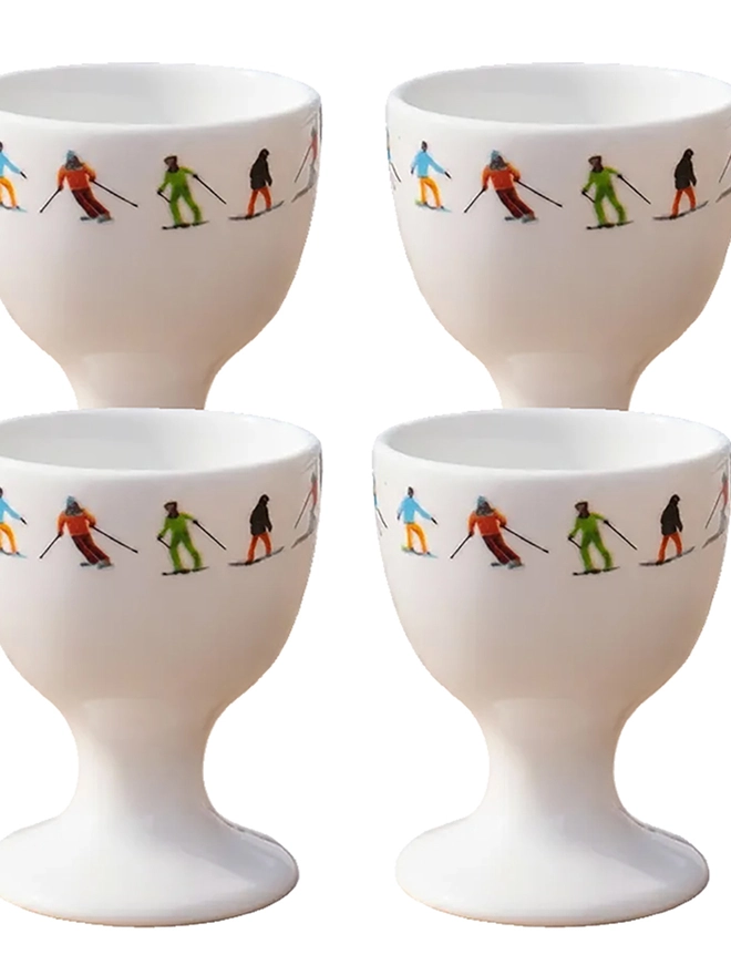 Ski Chain Egg Cup. A white egg cup patterned with a chain of multicoloured skiers on its rim. It is set against a plain, white background.