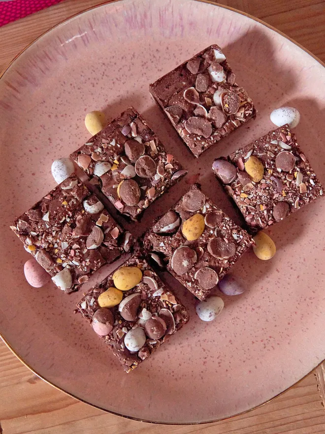 Easter Brookies (brownie top with a cookie base) on a round pink plate atop a wooden worktop
