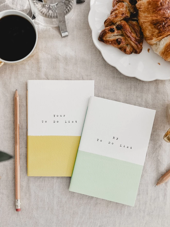 pair of notebooks.  one yellow and white with 'your to do list' and the other is green and white with 'my to do list' typed on the cover