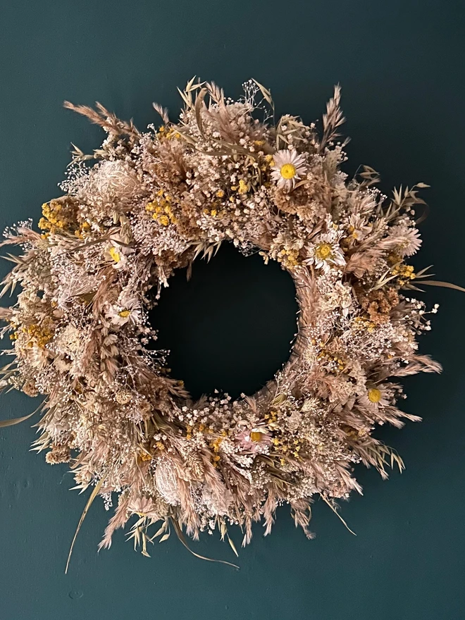 dried floral dried flower door wreath. a dried flower wreath made of various dried flowers and foliage hung on a forest green wall.