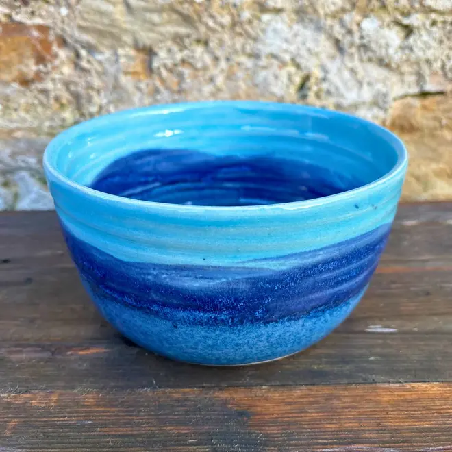 Landscape Ramen Bowl, a of colourful ramen bowl placed on a wooden surface in front of a brick backdrop. 