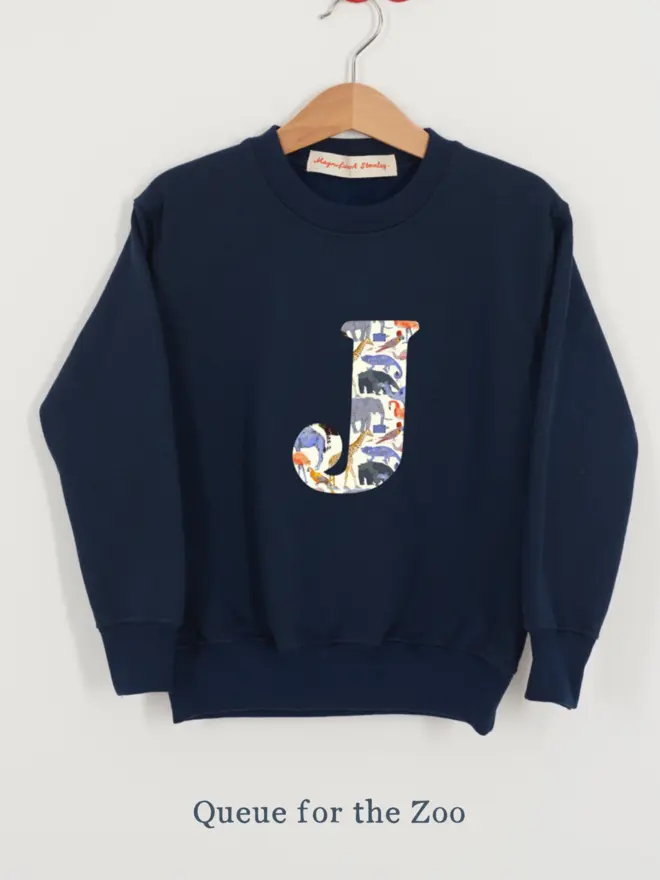 a navy kids sweatshirt with the initial J personalised in zoo animal liberty print on the front