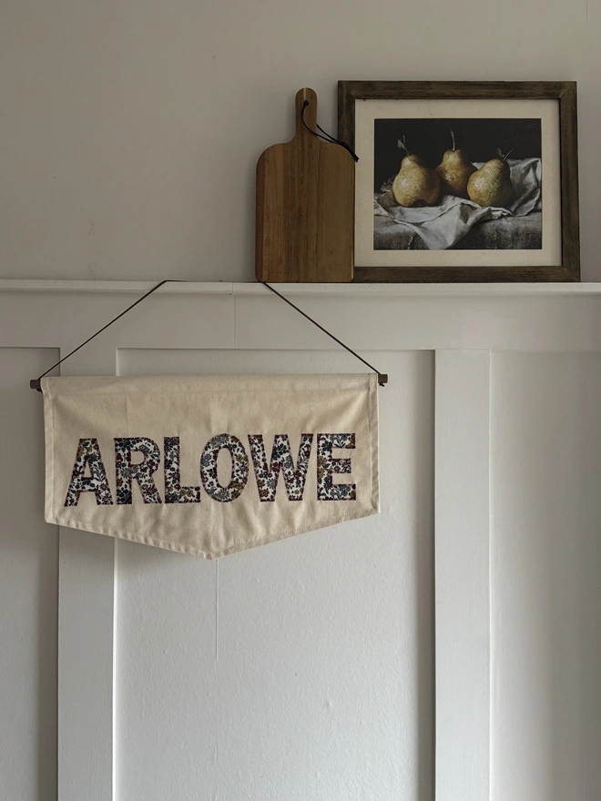 Personalised Fabric Name Banner.  Banner with the name ARLOWE in floral print letters hanging on a wall