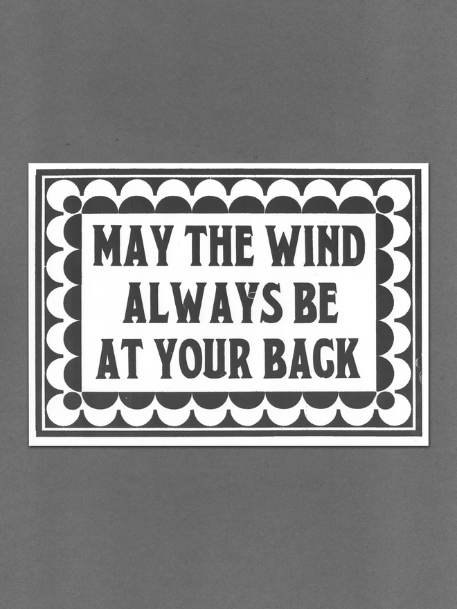 A3 letterpress print with vintage serif block font text design "may the wind always be at your back" surrounded by vintage art-deco style border made of semicircles and semi-circular cut-outs