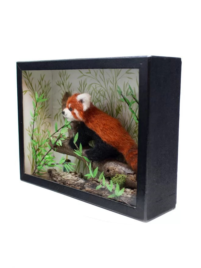 A miniature diorama featuring a red panda climbing a branch
