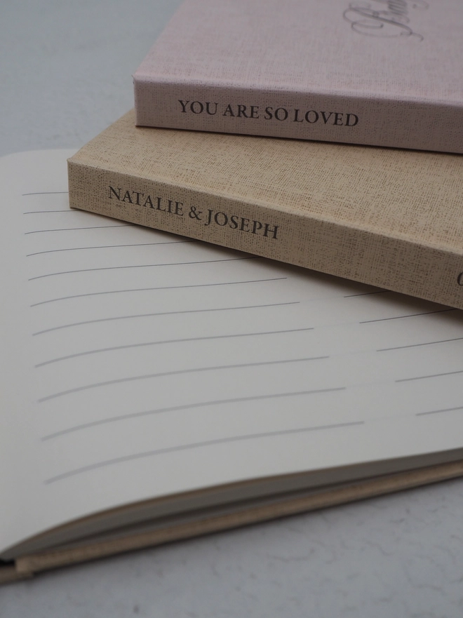 Personalised Baby Shower Guestbook. A close up of the spines of the book showing the linen embossed texture of the cover paper and the personalised text at the top of the spine