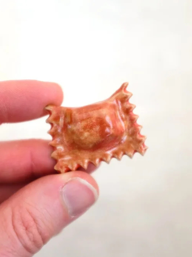 ceramic pasta magnet. a ceramic ravioli magnet photographed close up.