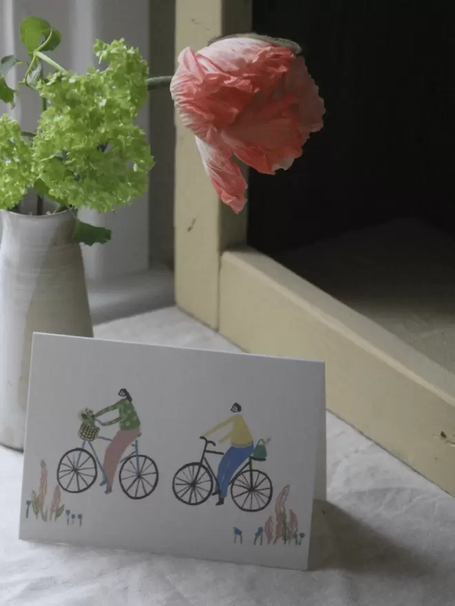 girl and boy on a bike greetings card