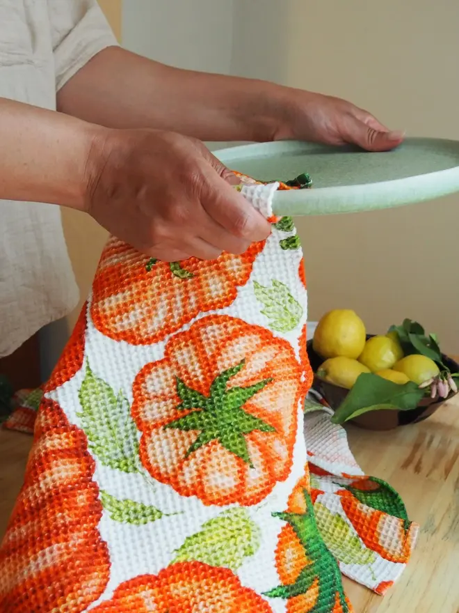 Tomato Waffle Tea towel, being used to clean a white bowl. 
