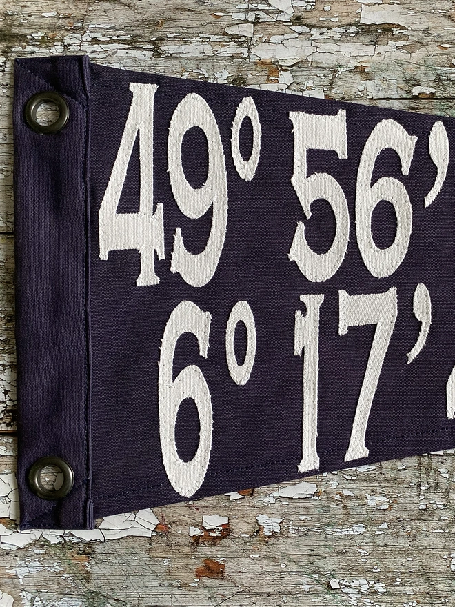 Detail of a coordinates pennant flag showing the ivory canvas numbers