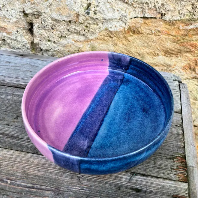 Landscape Pasta Bowl, a colourful pasta bowl on a wooden surface against a brick backdrop. 