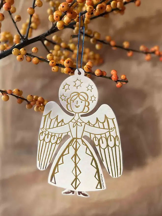 White and gold angel christmas tree ornament hanging from branch