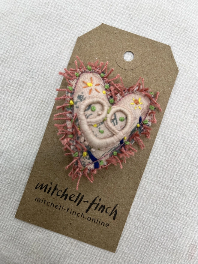 pink fringe brooch on label