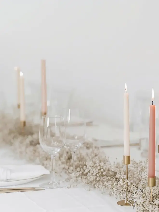 beige dinner candles on a long wedding table with wine glasses and flowers