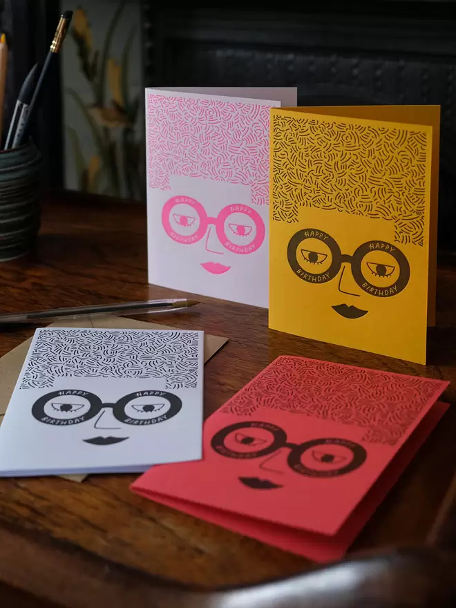 Four cards with a ladies face wearing glasses saying 'happy birthday'.