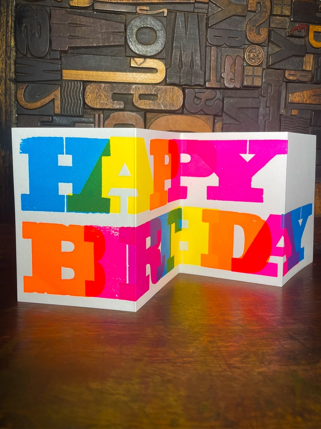 Artisan letterpress printed "Happy Birthday" concertina card featuring bold typography in six fluorescent inks with a deep impression print
