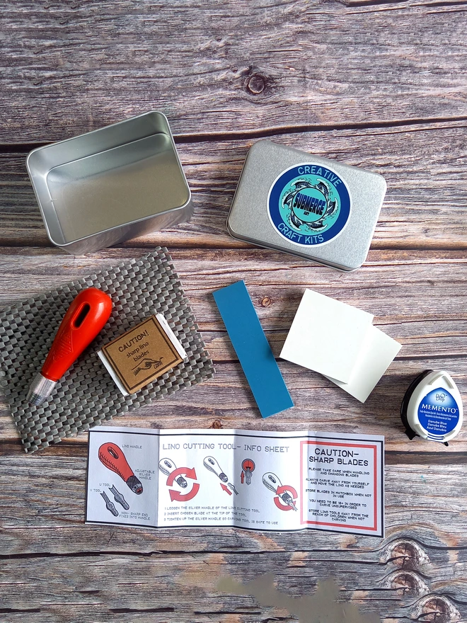 Stamp carving kit in a tin with carving tools, stamps, ink stamp pad and safety instructions
