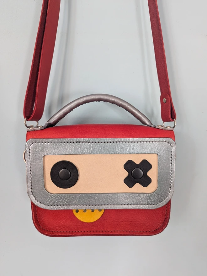 Hanging red leather robot cross body bag, front view close up.