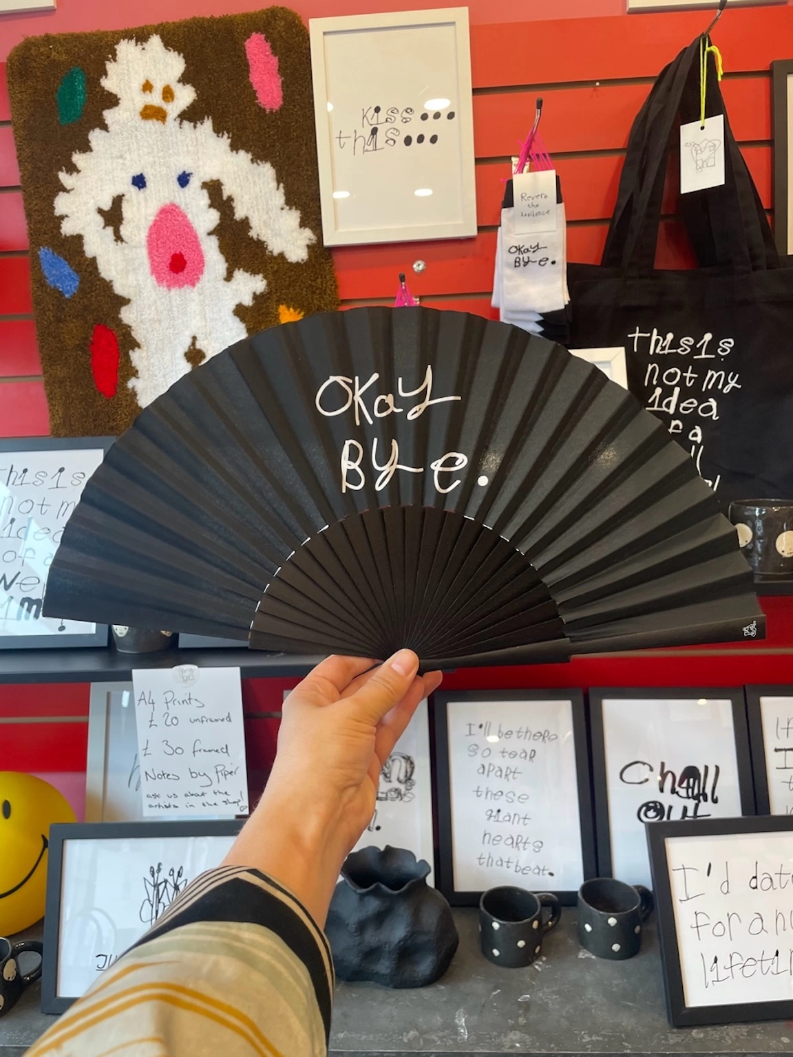 a black fan with piper with writing saying okay bye in the middle