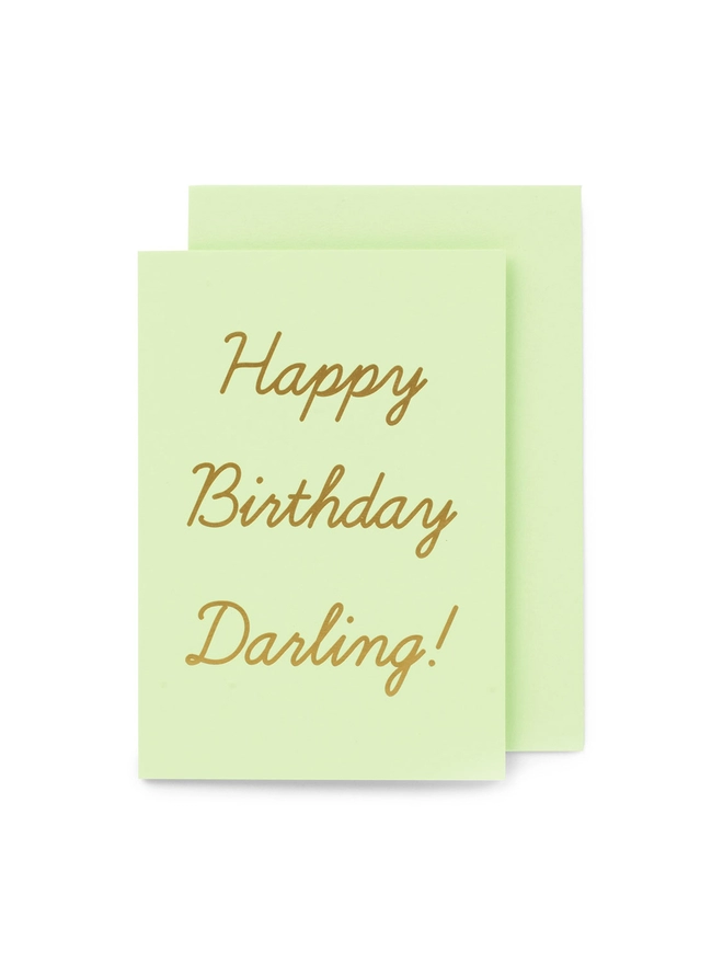 A mint green greeting card that says 'Happy Birthday Darling!' in gold foil