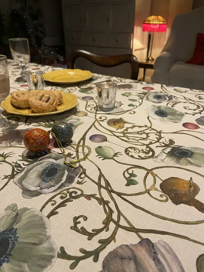 christmas robin tablecloth. a tablecloth with illustrated robins and baubles on a table.