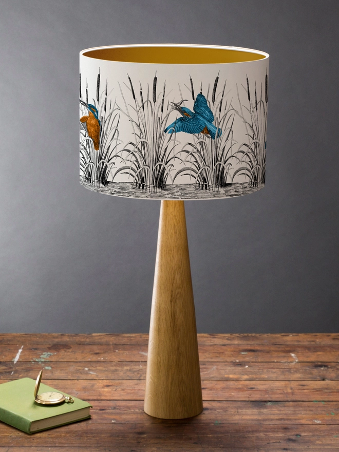 Handmade lampshade featuring vibrant kingfishers among bulrushes in a whimsical countryside-inspired design, combining nature, colour, and artisan style.