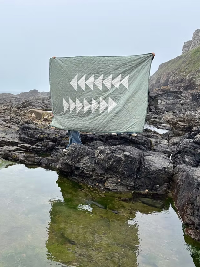 Flow Light Sage Green Linen Quilt. A green quilt with triangle design.