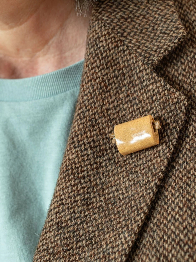 ceramic pastry pin badges. a ceramic pain au chocolat badge on a coat lapel.