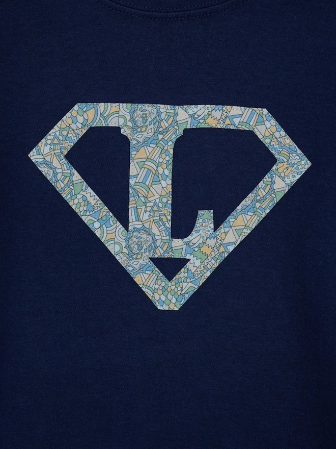 a personalised kids navy t-shirt with a superhero initial cut from liberty dragon print on the front
