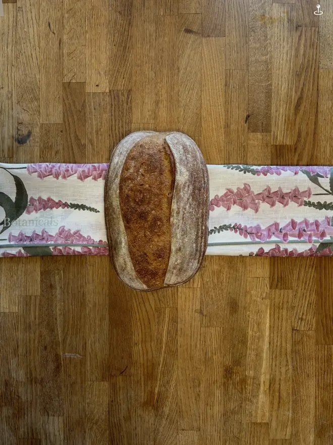 A loaf of home made bread wrapped in a foxglove design 100% linen tablecloth