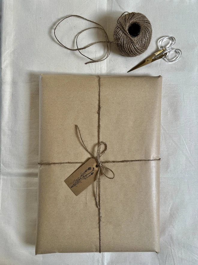 artwork gift wrapped in brown paper with a hand stamped flower tag and brown string bow