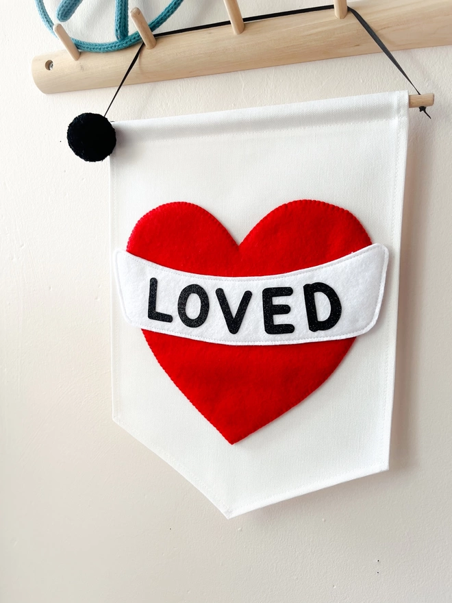 White banner with red heart saying the word loved