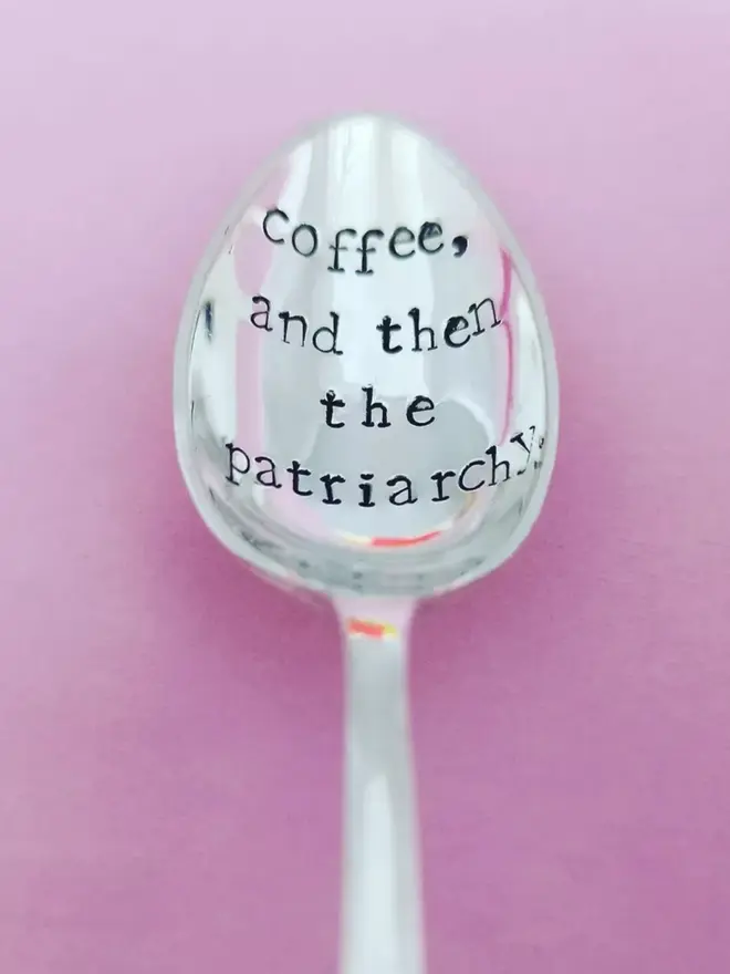 Coffee, and then the patriarchy stamped on a vintage silver plated spoon on a pink background