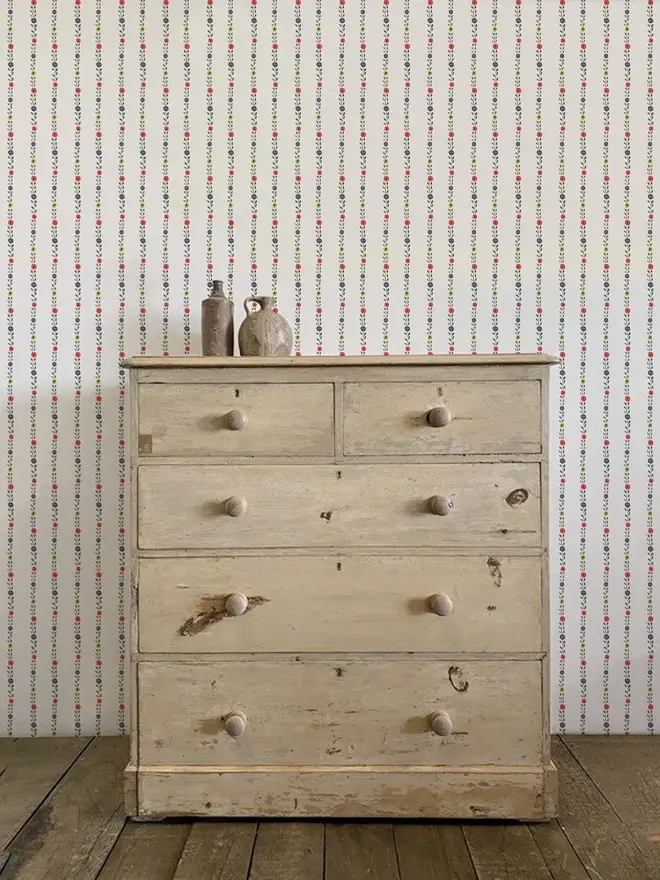 cottage core stripe illustrated wallpaper. a pale pink background wallpaper patterned with stripes of coloured flowers and leaves.