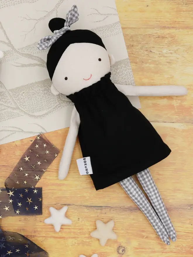 marrie top knot girl doll. a linen doll with a black dress and hair tied up with a grey bow.