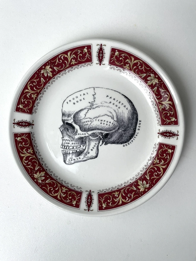 an ornate vintage plate with the image of a skull in the centre