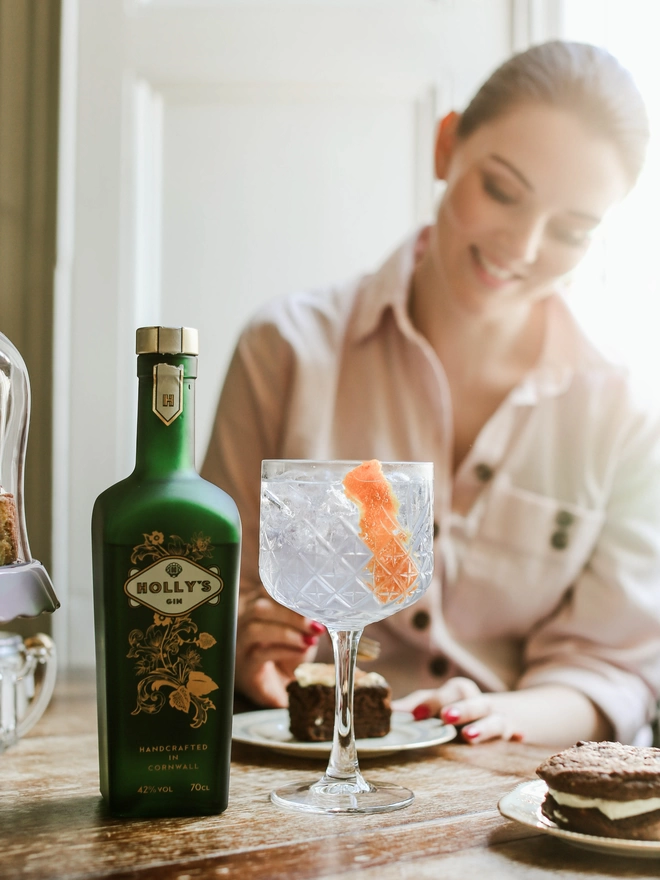 Holly eating cake next to a bottle of Holly's Gin and large G&T glass