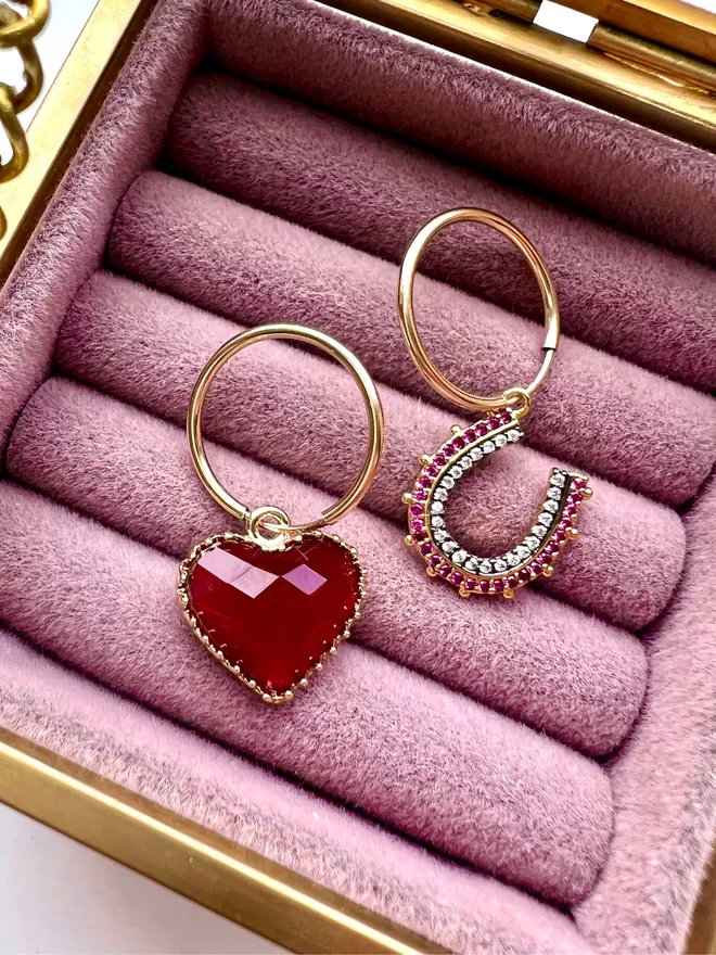 Mismatching gold hoop earrings with red heart and mini pink horseshoe charm